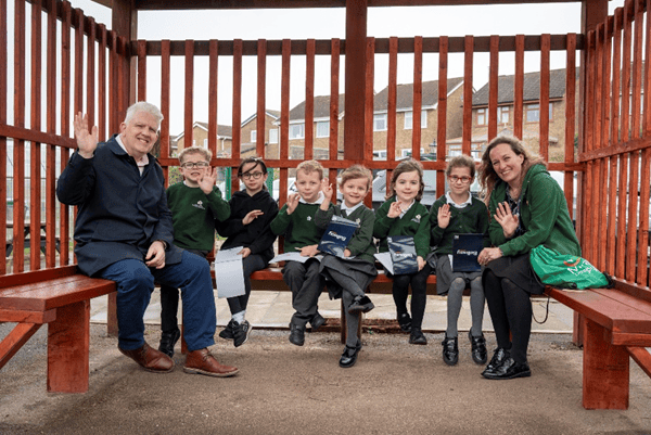 Bellway’s Simon Hughes and headteacher Emma Mignaud join pupils in the school’s refurbished parent shelter after the upgrade work.