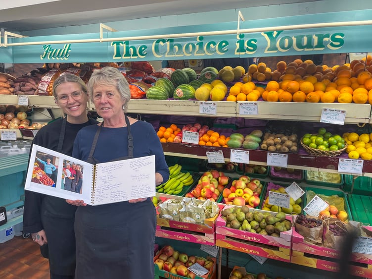 Greengrocer Pat Scott, holding a book of retirement wishes, with assistant Rachael Lewis.